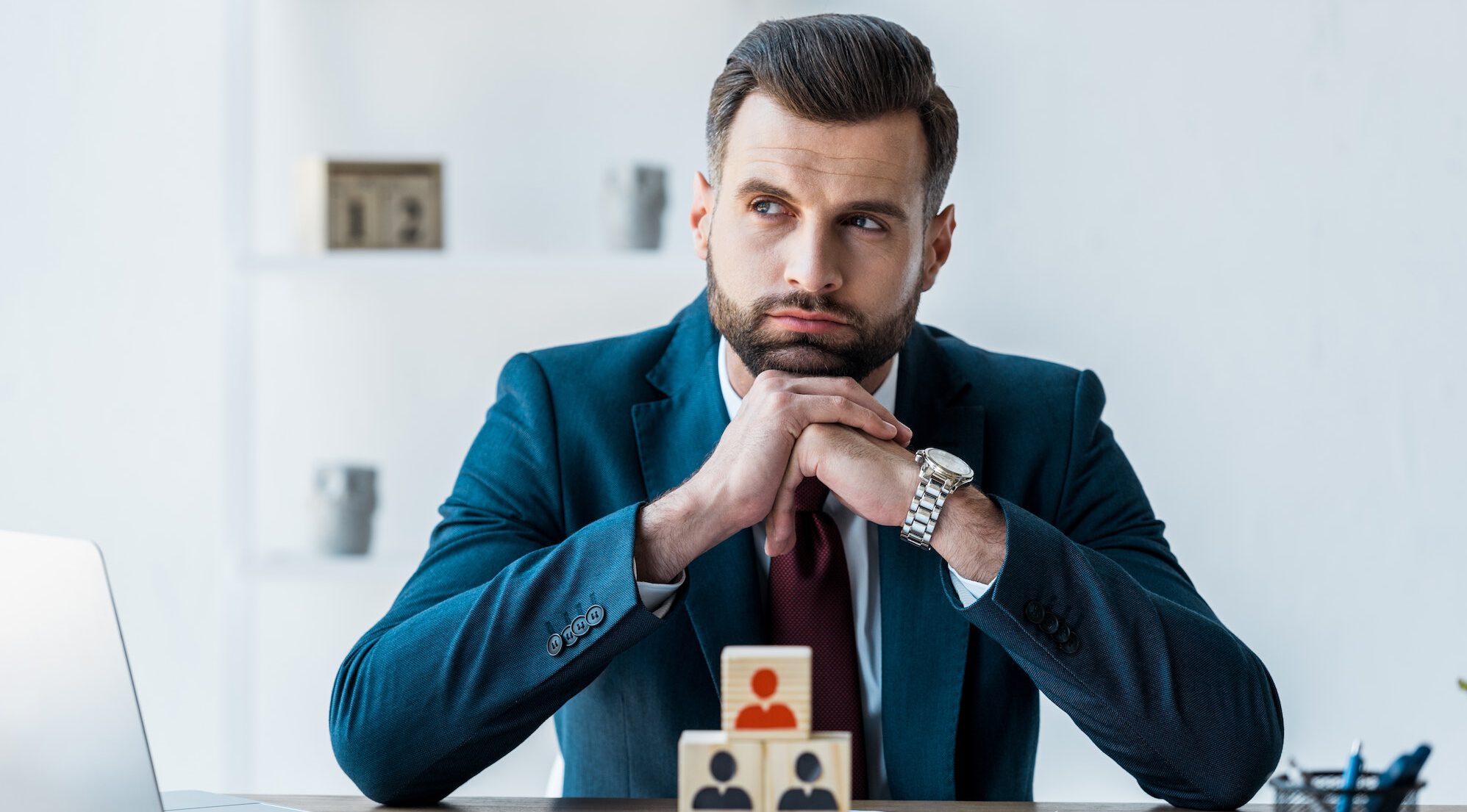 selective focus of pensive recruiter with clenched hands near wooden cubes